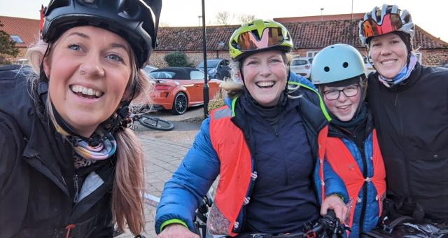 Three women pose for a selfie with a young girl. They're wearing cycle helmets