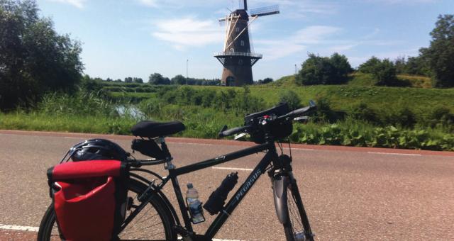 A bike parked on an empty cycle lane next to a windmill