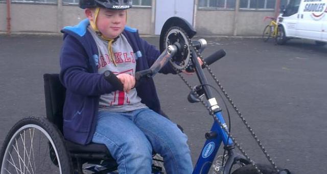 A young boy riding a hand trike