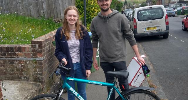 A young man and woman standing in the suburban street with bikes