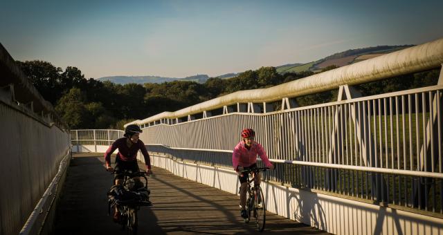 two women cycling over a bridge