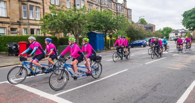 A group of riders on tandems ride along a residential street in Edinburgh