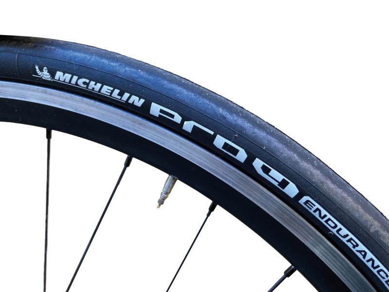 A close-up of the Michelin Pro 4 Endurance tyre showing the logo, on a bike wheel