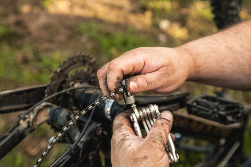 A person is using a chain tool to replace a bicycle chain