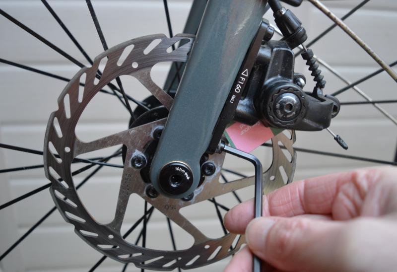 A person's hand can be seen adjusting a disc brake