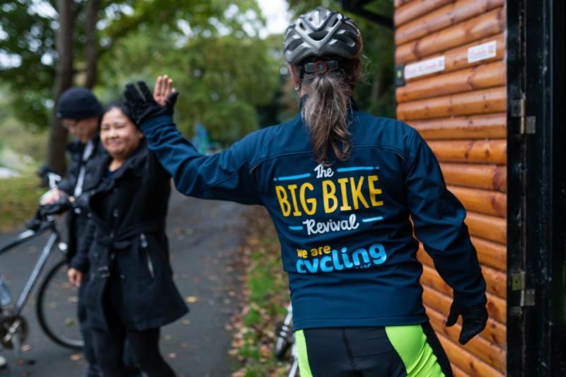 The back of a lady with a Cycling UK jacket and another lady in the background with a helmet on