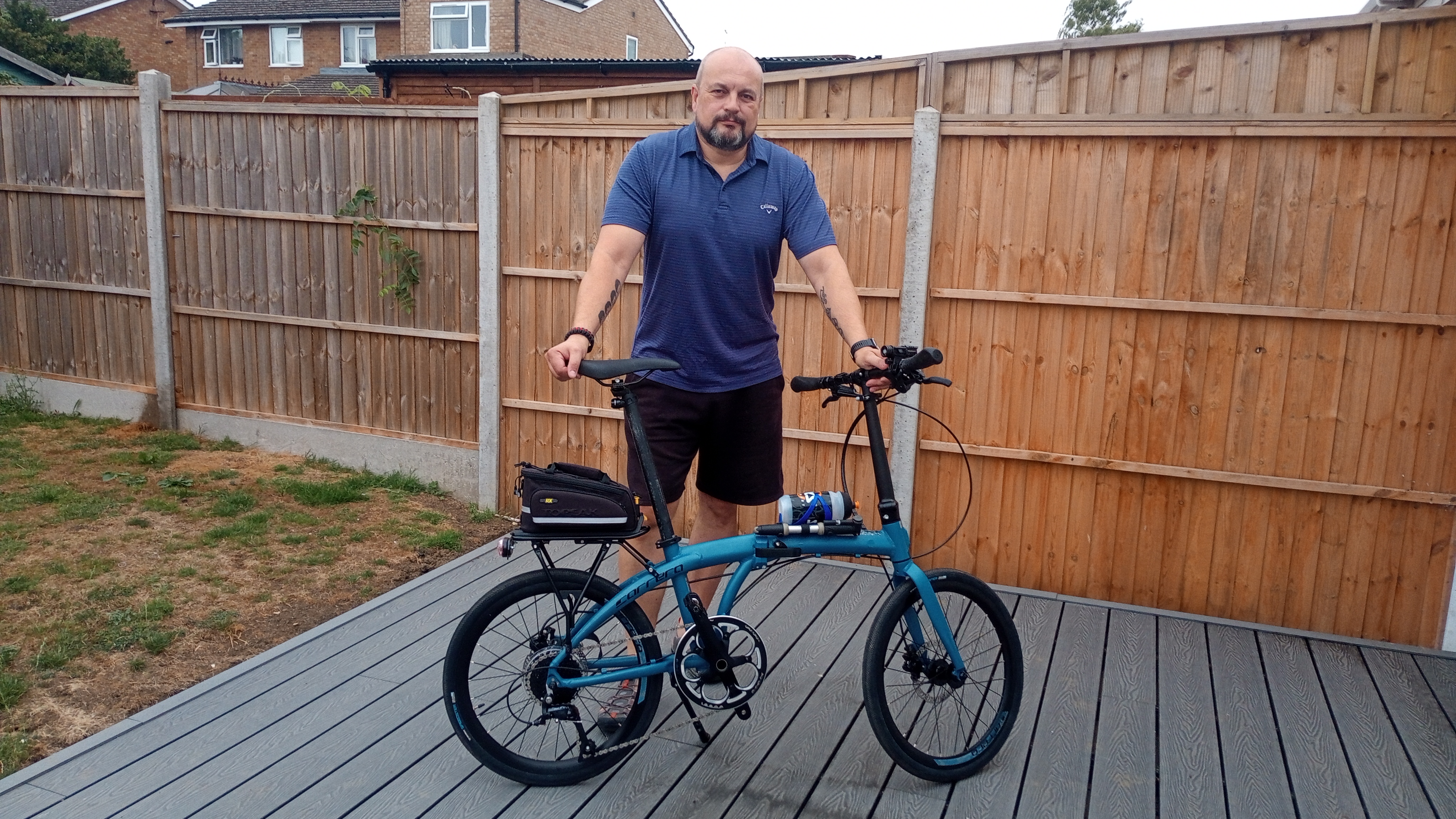 A man standing in his garden with a foldable bike