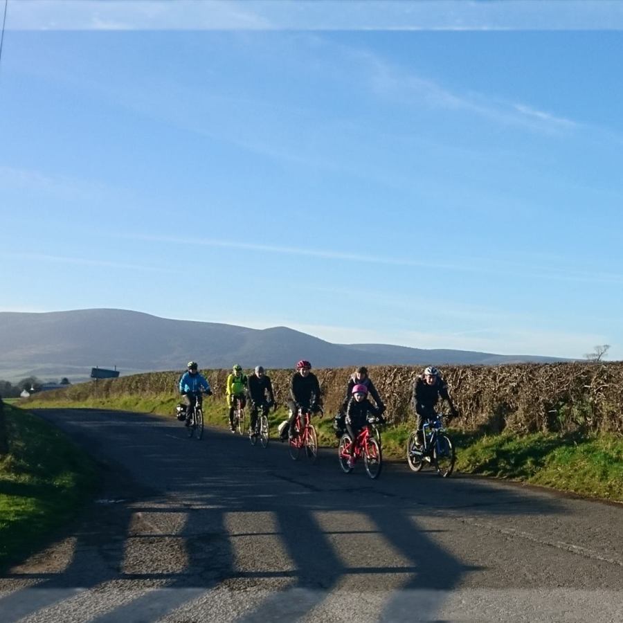 Cyclists on road enjoying the sunshine, with Criffel in the background.