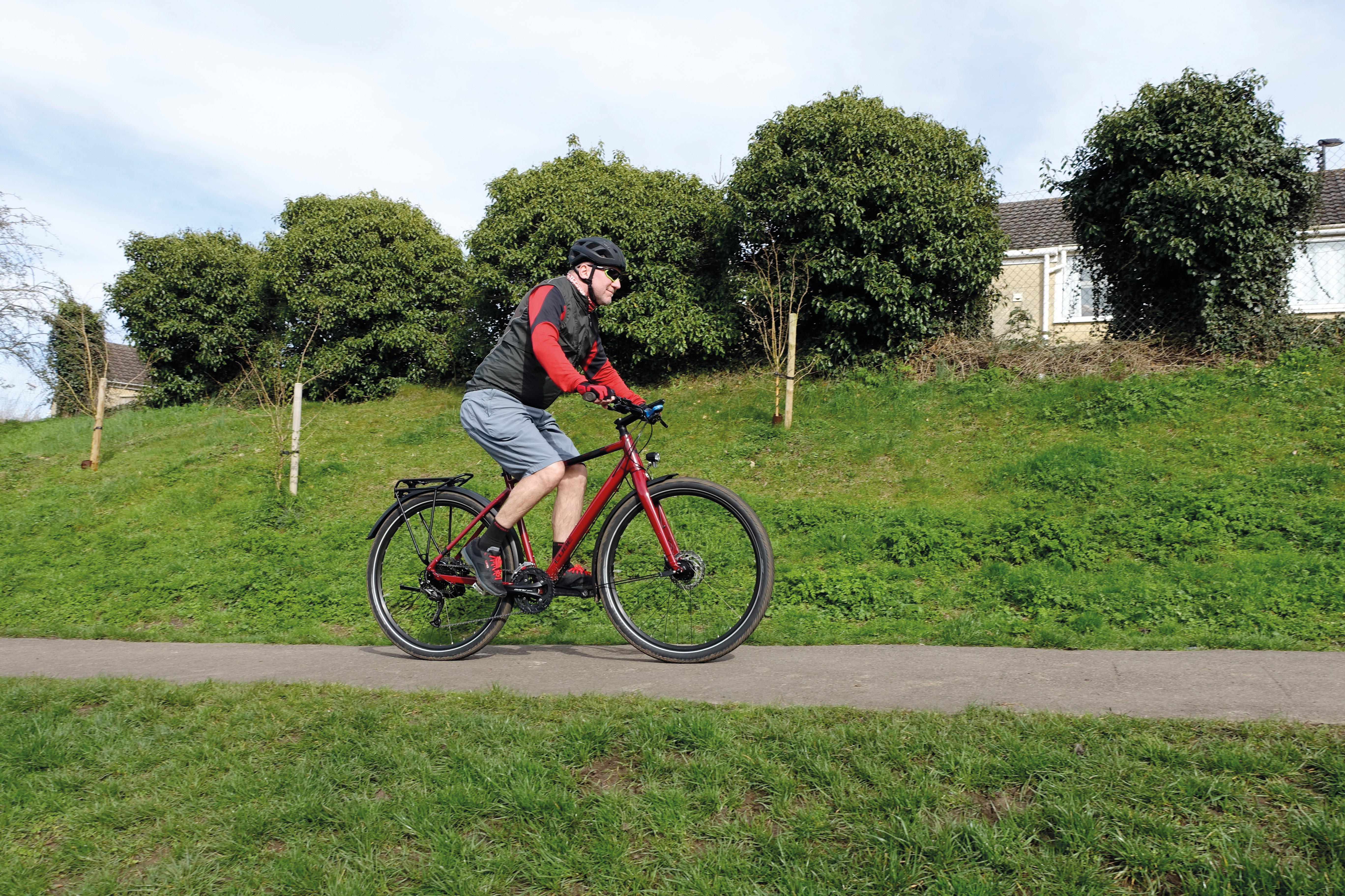 A man cycles along a cycle path on a red bicycle