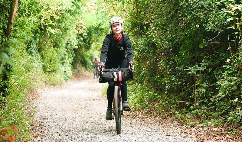a woman riding a bike through a woodland trail