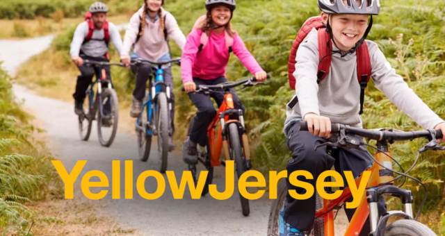 Children cycling in a line outside on a grey path with the yellow jersey logo overlay