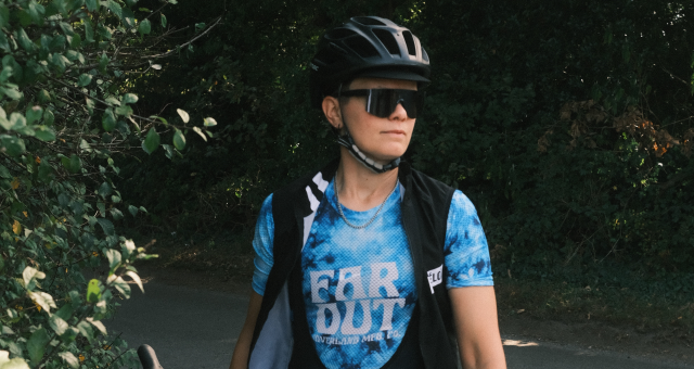 A woman in cycling clothing is standing looking away from the camera