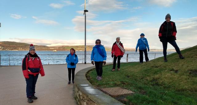 Group of volunteers and staff standing in a row on promenade at seafront