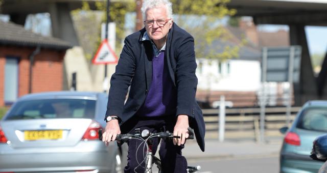 A man in normal clothing is cycling on an urban street
