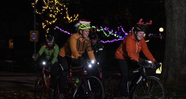Cyclists riding at night wearing Christmas outfits.