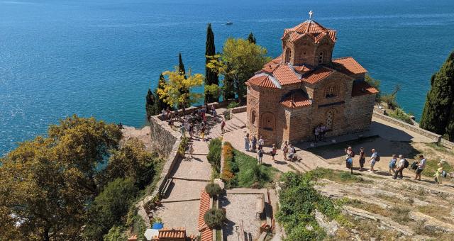 Looking down on a red brick church on a cliff top overlooking a blue sea