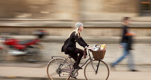 Woman cycling with shopping in her basket