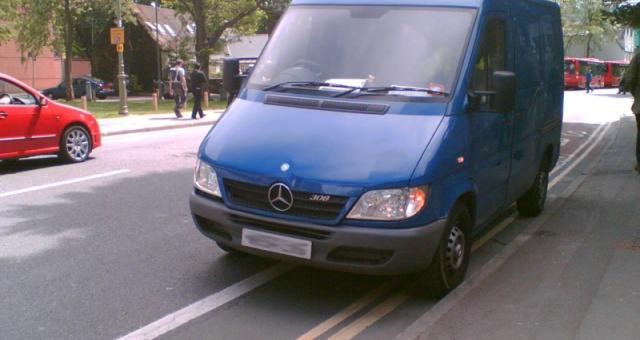 Van parked in mandatory cycle lane with double yellow line.
