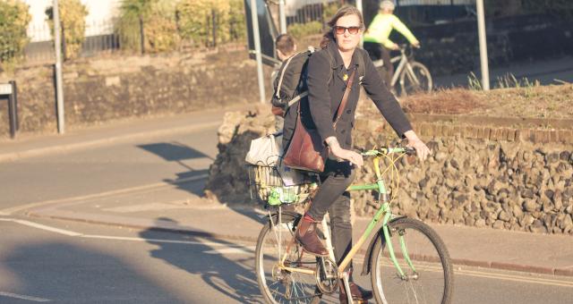 Woman cycles with shopping in a basket on back of her bike