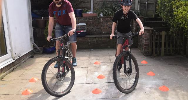 A man and his son practice on bicycles in a small patio area