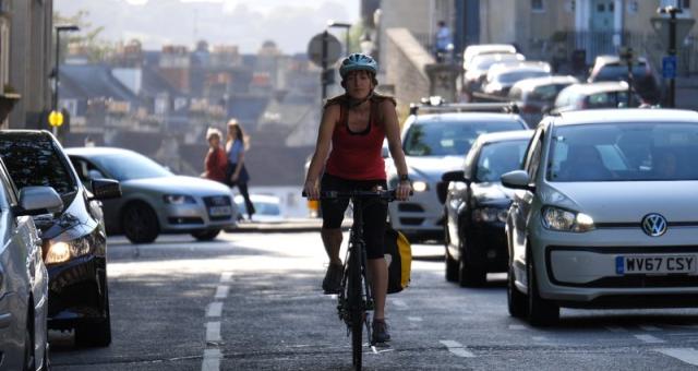 Woman cycles alongside traffic