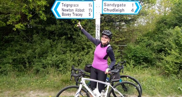 Cyclist pointing at a road sign. Photo by South Devon CTC