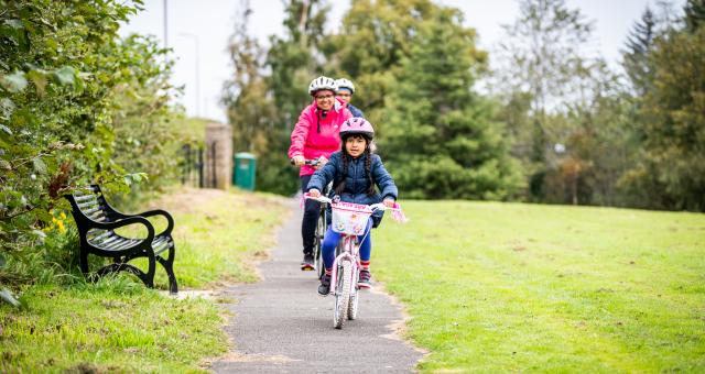 A family with young daughter cycling in the park