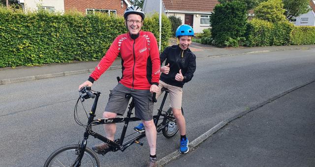 boy and man sitting on tandem in residential street