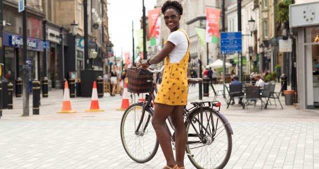 Woman standing next to a bike in a high street