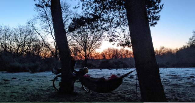 A bikepacker on a frosty morning in their hammock