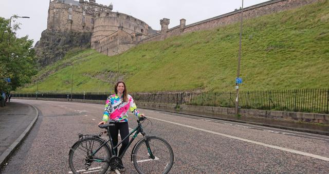 Woman with bike standing on road under Edinburgh Castle
