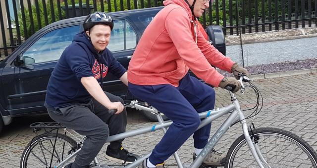 Father and son riding tandem in residential street
