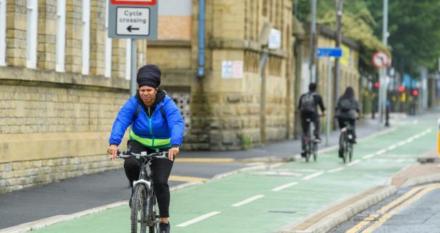 A woman in a blue jacket riding along a designated cycle lane with buildings to her right