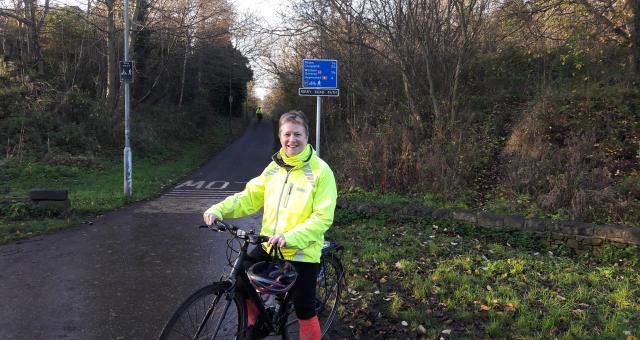 woman with bike on cycle path standing in front of signpost