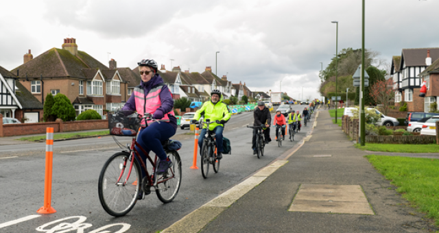 A group of cyclists riding alongside the kerbside in a residential area