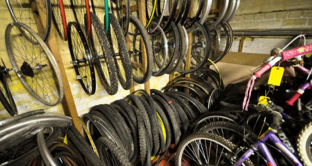 A row of bike wheels in a storage space in a workshop with yellow walls