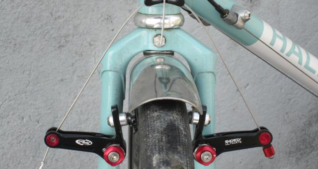 The red and black front cantilever brake in situ on a pale turquoise bike