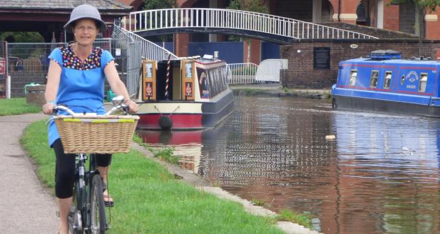 Woman dressed stylishly riding a bicycle on canal towpath