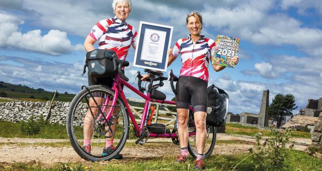 Two ladies stand by a tandem holding a Guinness World Record