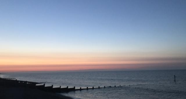 Sun setting on the sea, a beach in the foreground