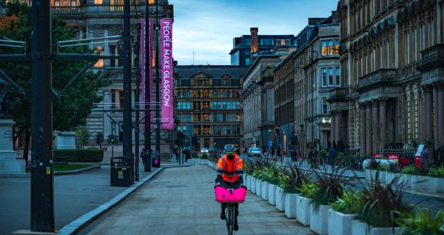 man cycling past planters in George Square, Glasgow