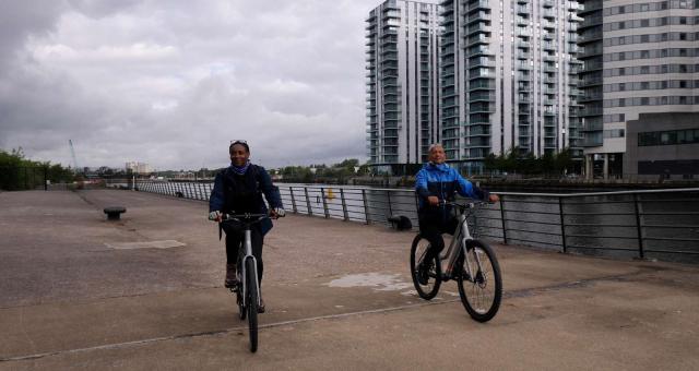 Two people pedalling next to MediaCity in Salford, Manchester prior to the Cycling made e-asy launch