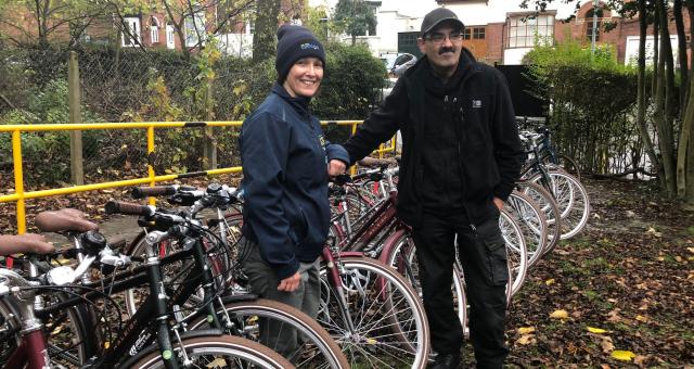 man and woman standing outdoors with a large number of new identical bikes