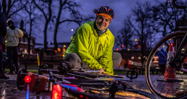 A man putting lights on his bike at dusk