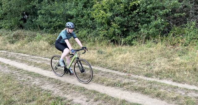 A woman cycles along a wooded track on an off-road bicycle