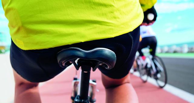 The rear view of a bicycle saddle on a bicycle, a man sits on the saddle