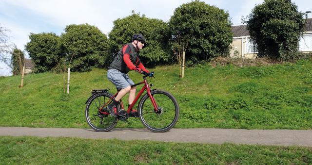 A man cycles along a cycle path on a red bicycle