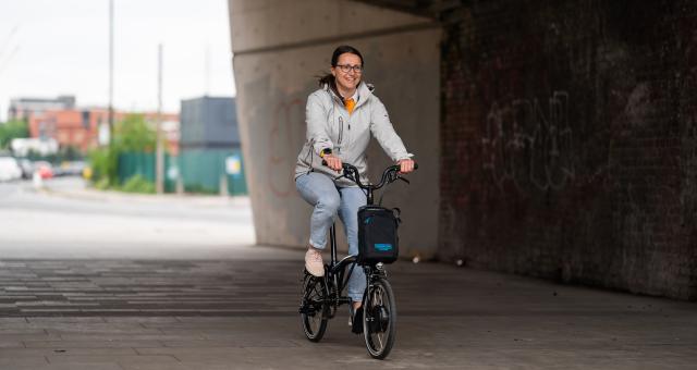 Woman pedals electric Brompton under building