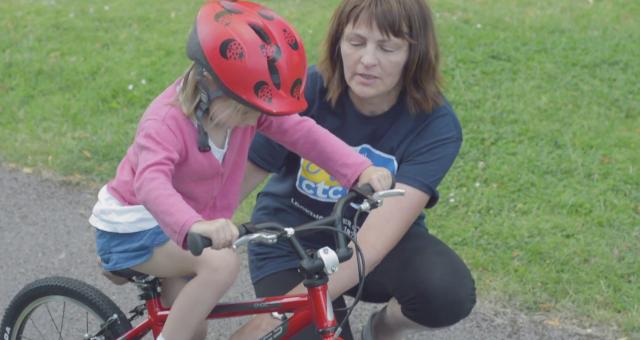 Julie teaches a four year old girl to learn to ride a bike