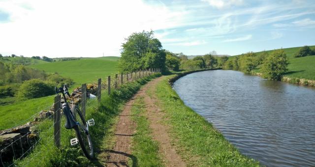 A unicycle on a towpath next to a canal in summer.